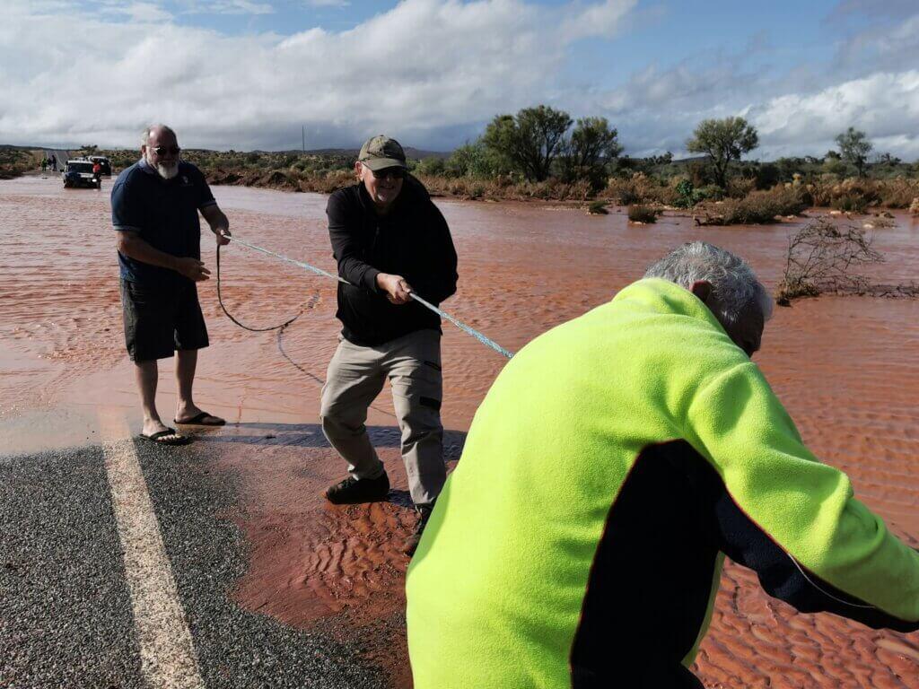 Martin (centre) and Rick (right) winch a stranded vehicle out of the creek