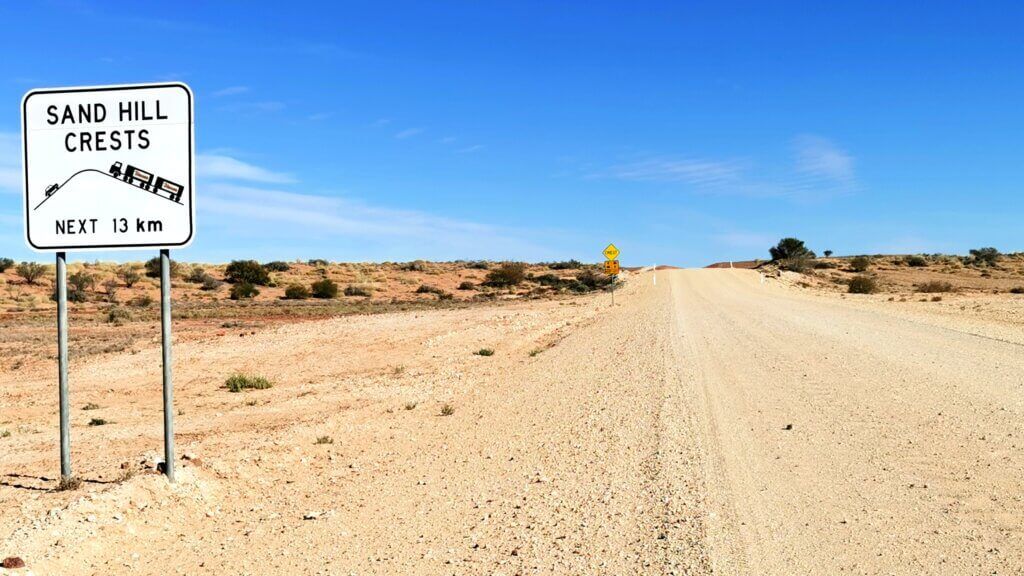 All I can see is a sandy road leading up a hill and a the side of the road there is a signing promising 13 km of the same