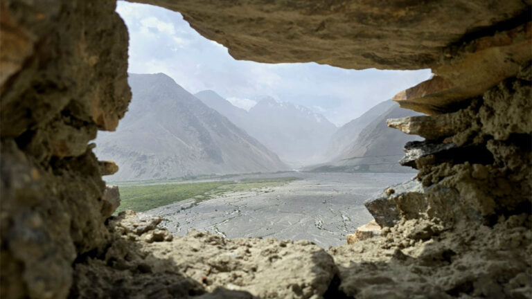 a view through a hole in the wall into the wakhan valley with mountains on each side