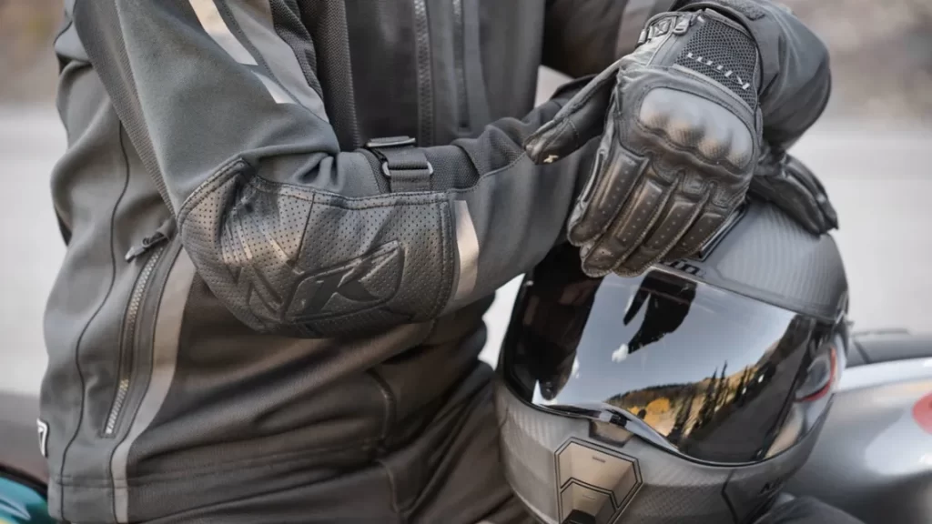 closse up of a motorcyclist sitting on his bike wtih the crash helmet on the tank and his arms folded on top