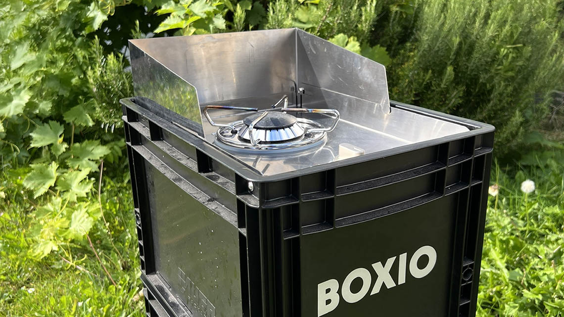 boxio coo camping gas stove outside in front of rosemary bush